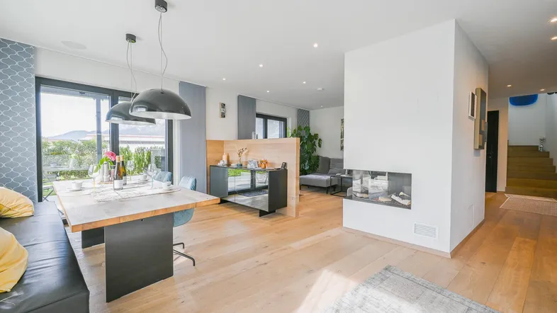Helles, offenes Wohn- und Esszimmer mit Holzboden, modernem Kamin und Zugang zum Garten.