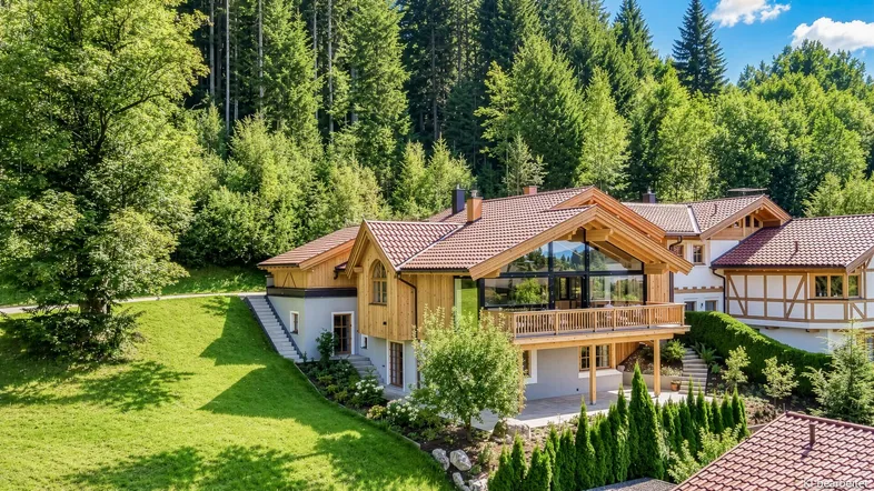 Großzügiges Chalet in den Bergen mit Holzfassade, großen Glasflächen und umgebender Natur.