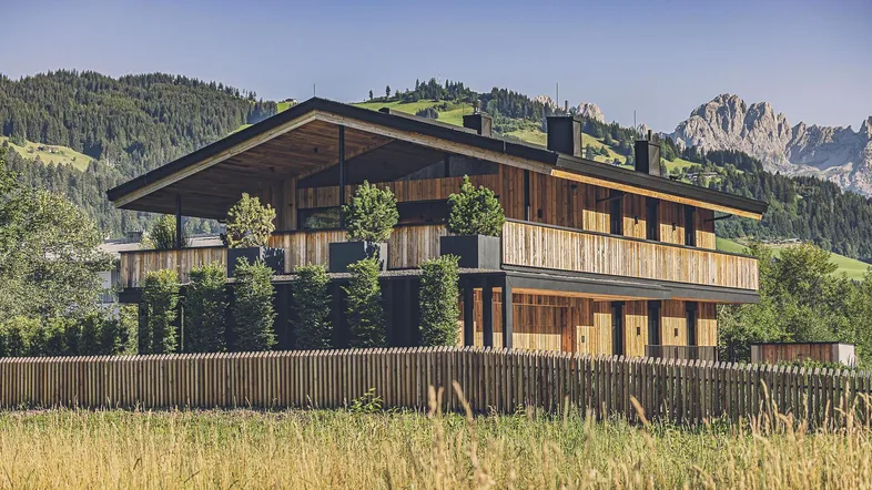 Modernes Holzhaus im alpinen Stil mit Bergblick und umliegender Natur.