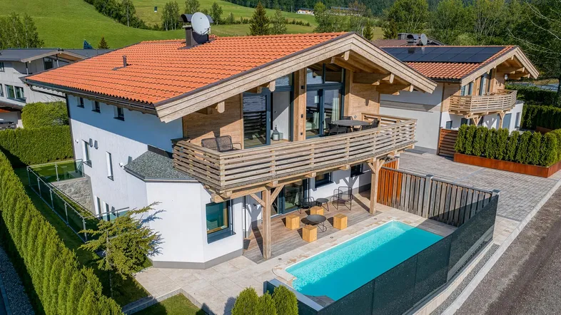 Modernes Chalet mit privatem Pool, Balkon und Bergblick in grüner Umgebung.