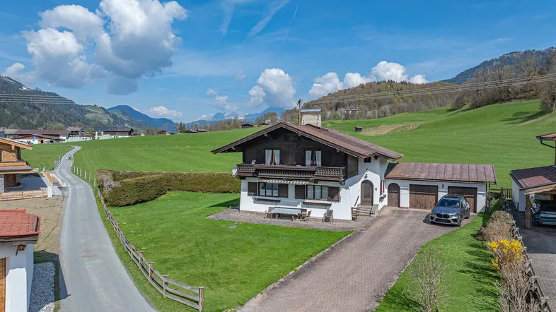 Traditionelles Haus im alpinen Stil mit großem Garten, Auffahrt und Bergblick.