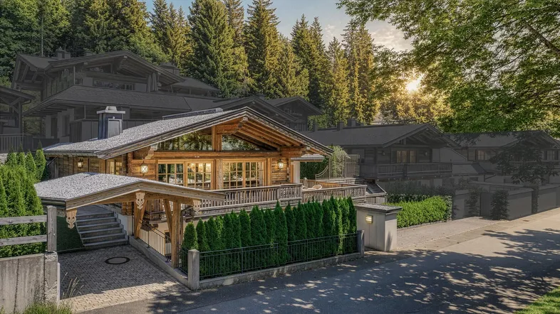 Traditionelles Holzchalet mit großzügiger Architektur und Carport, eingebettet in eine grüne Berglandschaft.