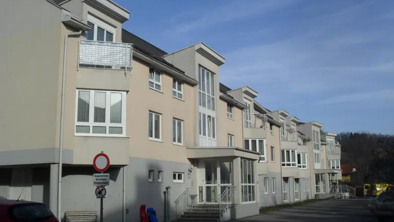 Moderne Gebäudefassade mit mehreren Balkonen und großen Fenstern unter blauem Himmel.