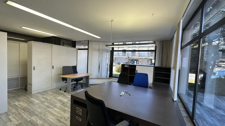 Geräumiges Büro mit großen Fenstern, modernen Möbeln und hellem Holzboden, ideal für produktives Arbeiten.