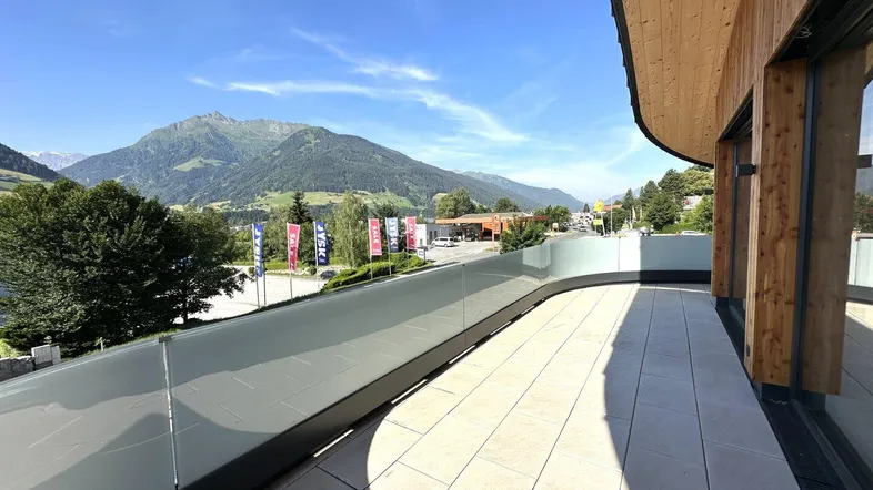 Geräumige Terrasse mit moderner Glasbrüstung und weitem Blick auf die umliegende Berglandschaft.
