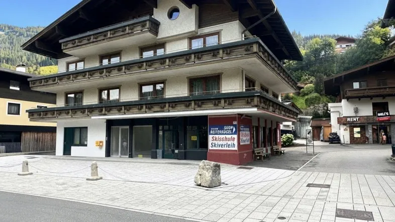 Mehrstöckiges Gebäude mit traditioneller Holzfassade und Balkonen in einer bergigen Umgebung.