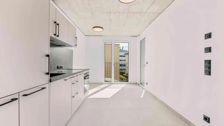 Moderne Einbauküche mit hellen Fronten, Fliesenboden und Zugang zu einem französischen Balkon.