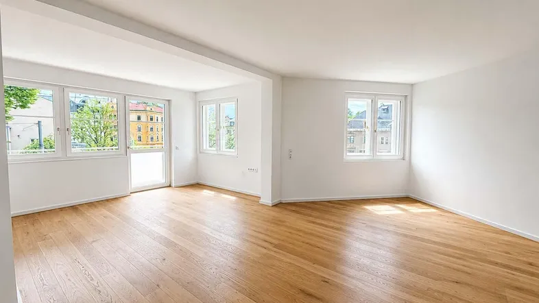 Helles und geräumiges Wohnzimmer mit neuem Parkettboden und Zugang zum Balkon.
