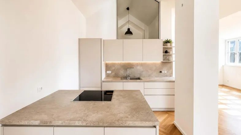 Moderne Küche mit Kücheninsel, Induktionskochfeld und hohen Decken in einem hellen Raum.