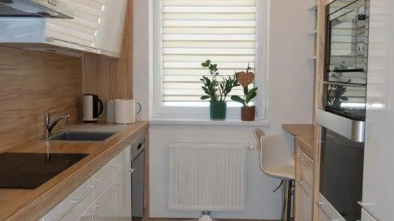 Moderne, helle Küche mit weißen Hochglanzfronten, Holzarbeitsplatte und integrierten Geräten.
