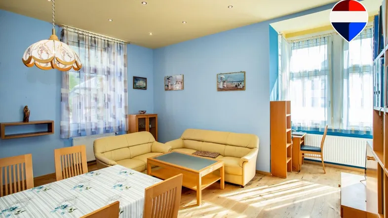 Helles Wohn- und Esszimmer mit blauen Wänden, gelber Decke und Holzboden.