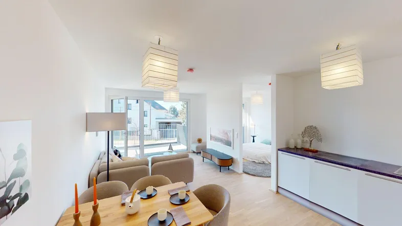 Heller, offener Wohn- und Essbereich mit modernem Design, Holzboden und Zugang zum Balkon.
