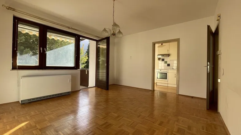 Geräumiges Wohnzimmer mit Parkettboden und Zugang zum sonnigen Balkon.