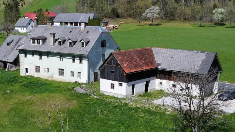 Ländliches Anwesen mit mehreren historischen Gebäuden, umgeben von grünen Wiesen und Bäumen.