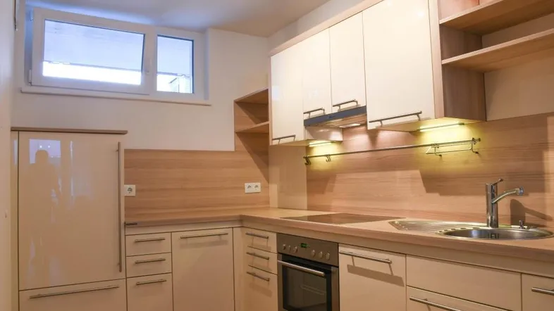 Moderne Einbauküche mit hellen Fronten, Holzoptik-Arbeitsplatten und integrierten Geräten.