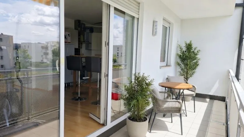 Heller Balkon mit Fliesenboden, Sitzgelegenheiten und Blick auf die Umgebung.