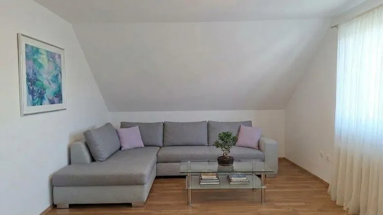 Helles Wohnzimmer im Dachgeschoss mit gemütlichem Ecksofa, Couchtisch und Laminatboden.