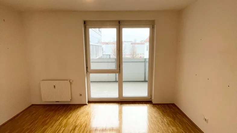 Helles Wohnzimmer mit Parkettboden und direktem Zugang zum Balkon.