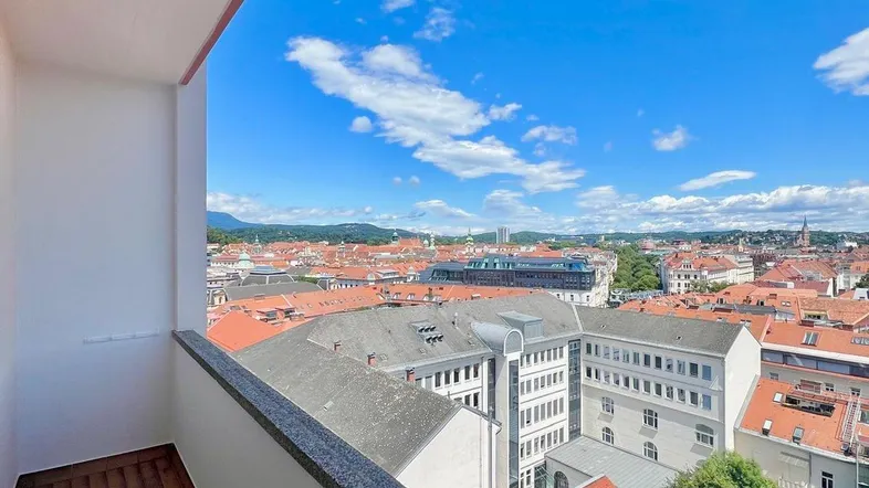Balkon mit Fliesenboden und weitem Blick über die Stadt und die umliegenden Berge.