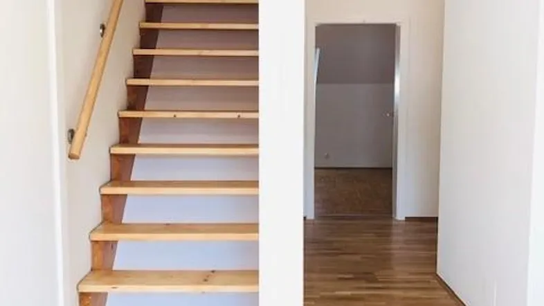Heller Flur mit Holztreppe und Parkettboden, der zu weiteren Räumen führt.