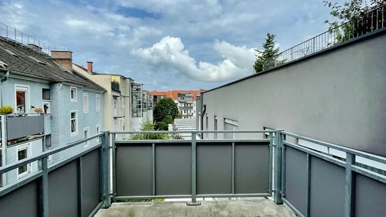 Balkon mit Blick auf die umliegenden Gebäude und den Himmel unter bewölktem Wetter.