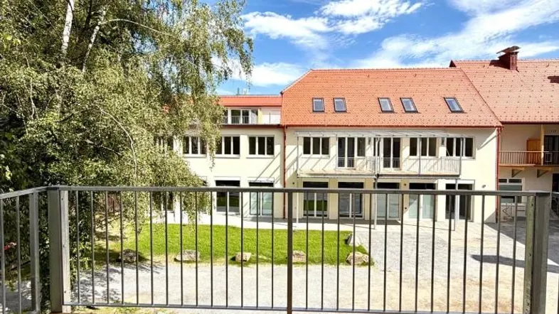 Blick vom Balkon mit Holzfußboden auf den Innenhof und das Gebäude.