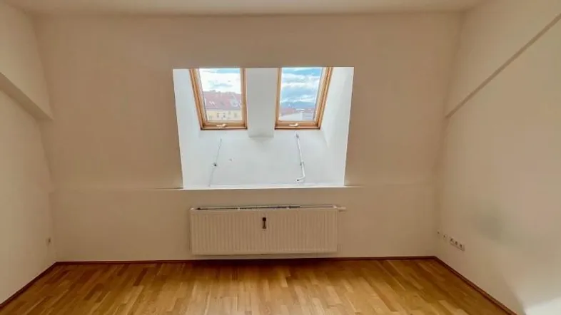 Helles Zimmer im Dachgeschoss mit Holzboden und zwei Dachfenstern, ideal als Schlafzimmer nutzbar.