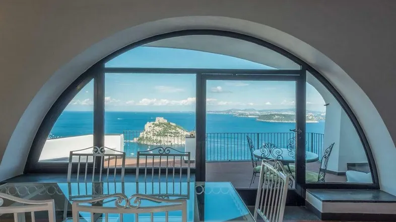 Heller Essbereich mit gewölbtem Fenster und atemberaubendem Meerblick auf die Küste.