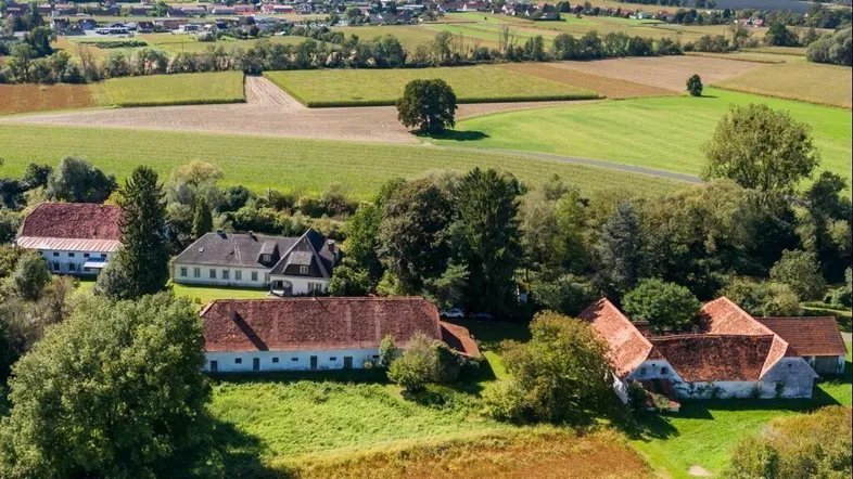 Ländliche Ansicht von mehreren Gebäuden und weiten Feldern in einer grünen Umgebung.