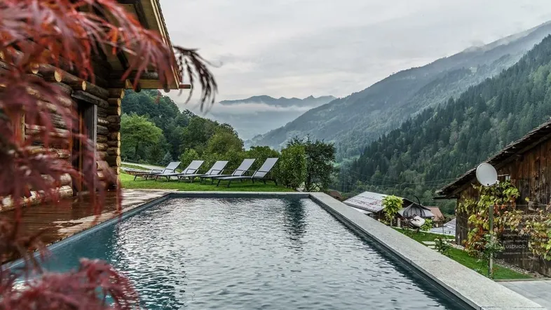 Infinity-Pool mit atemberaubendem Bergblick und Holzchalet im alpinen Stil.
