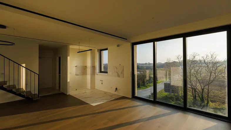 Helles Wohnzimmer mit Holzboden, großen Schiebetüren und weitem Blick ins Grüne.