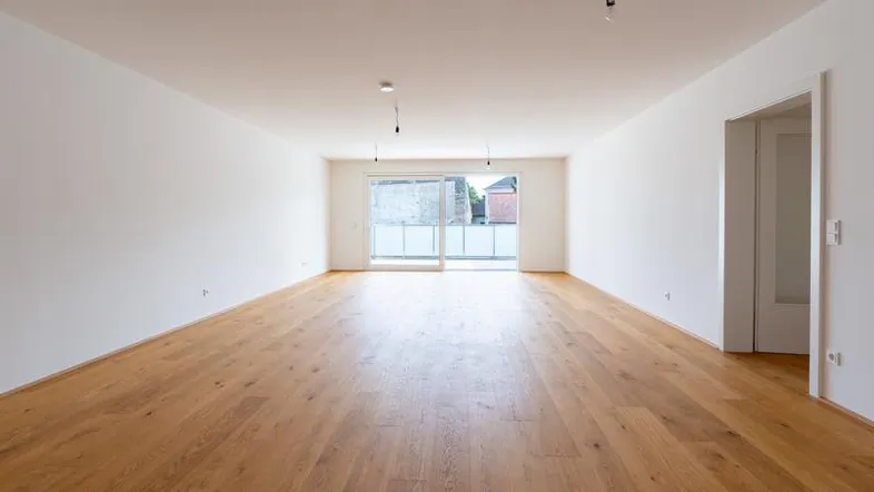 Helles, geräumiges Zimmer mit neuem Parkettboden und Zugang zu einem Balkon.