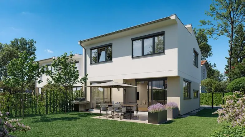 Modernes Reihenhaus mit großer Terrasse, Garten und viel Grünfläche unter blauem Himmel.
