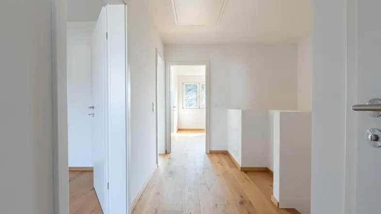 Heller Flur mit Holzboden und Zugang zu mehreren Zimmern sowie einer Dachluke.