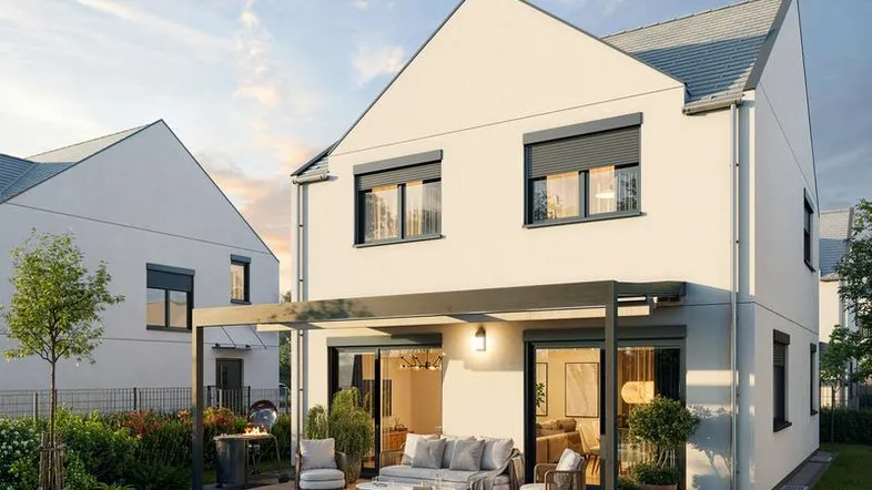 Moderne Hausrückseite mit großer Terrasse, Pergola und gepflegtem Gartenbereich bei Sonnenuntergang.