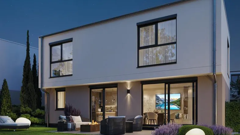 Moderne Hausfassade mit großen Fenstern, Terrasse und gemütlichem Gartenbereich am Abend.