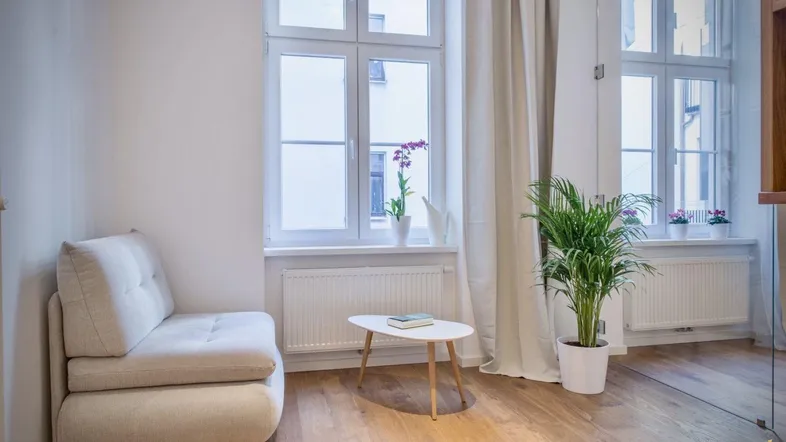 Helles Wohnzimmer mit Holzboden, großen Fenstern und einem bequemen Sessel.