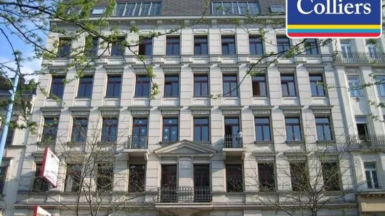 Klassisches Altbaugebäude mit mehreren Stockwerken und vielen Fenstern in einer städtischen Umgebung.