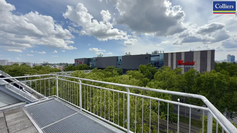 Dachterrasse mit Blick auf das Donau Zentrum und die umliegende Stadtlandschaft unter einem bewölkten Himmel.