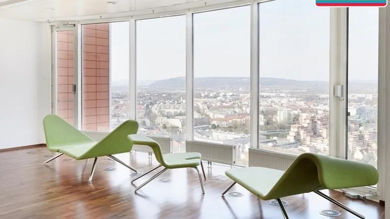 Moderner Loungebereich mit großen Fenstern, die einen weiten Blick über die Stadt bieten und bequemen Sitzgelegenheiten.