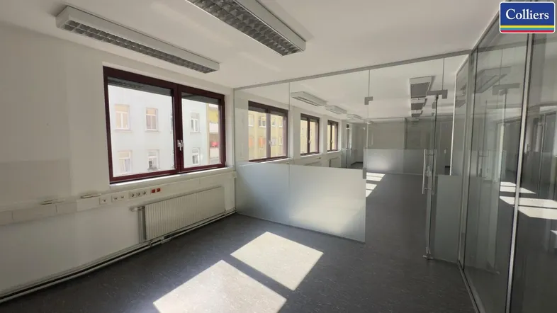 Helles Großraumbüro mit großen Fenstern, Glaswänden und viel Tageslicht, ideal für moderne Arbeitsumgebungen.