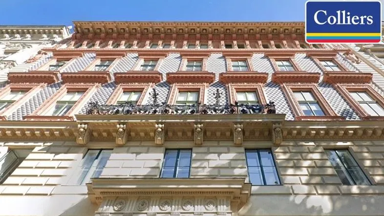 Historische Fassade eines Gebäudes mit reich verzierten Balkonen und großen Fenstern, die auf die Straße blicken.