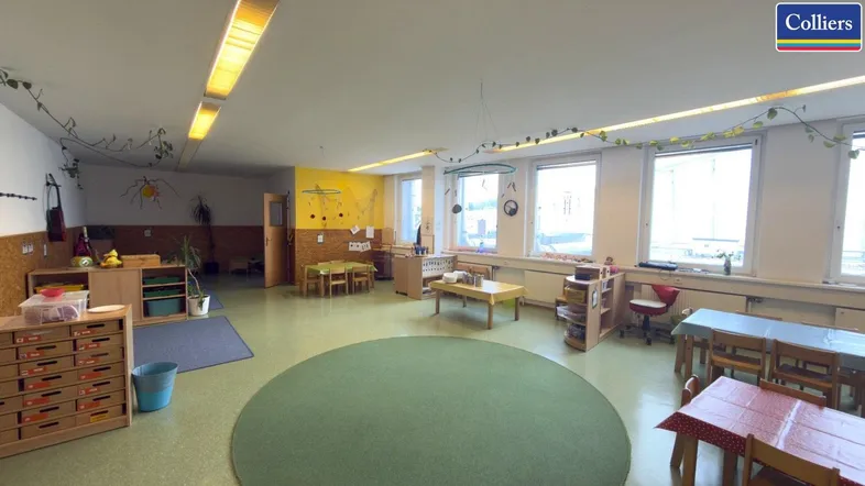 Heller, geräumiger Innenraum mit kindgerechter Einrichtung und großen Fenstern, ideal für eine Kindertagesstätte.