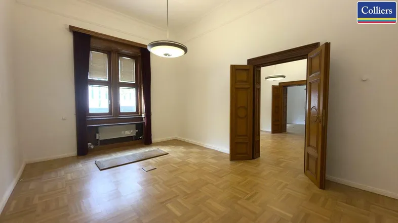 Geräumiger Wohnraum mit Fischgrätparkett, hohen Decken und großen Holzfenstern, bereit zur individuellen Gestaltung.