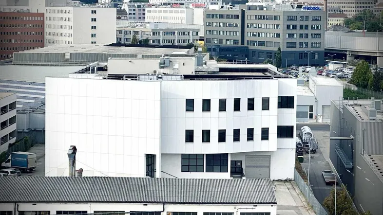Luftaufnahme eines Gewerbegebiets mit modernen Gebäuden und städtischer Skyline im Hintergrund.