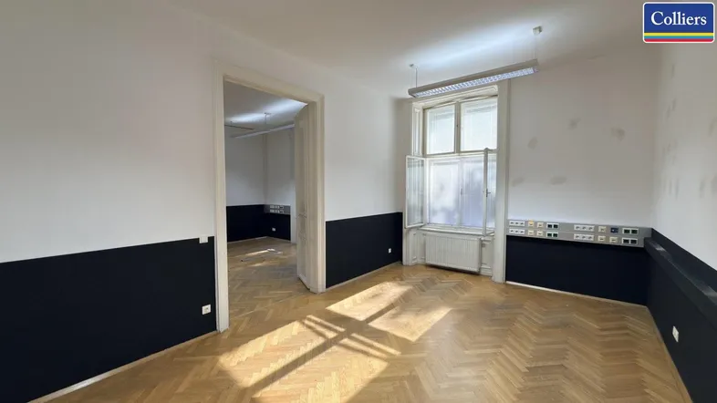 Geräumiges Büro mit Fischgrätparkett, großen Fenstern und vielen Steckdosen, bereit zur individuellen Gestaltung.