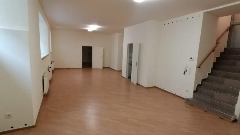 Geräumiger, heller Raum mit Laminatboden und einer Treppe, ideal für verschiedene Nutzungen in einem gepflegten Zustand.