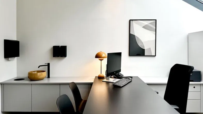 Modernes Büro mit Dachfenster, minimalistischer Einrichtung und integriertem Waschbecken in einem hellen Raum.