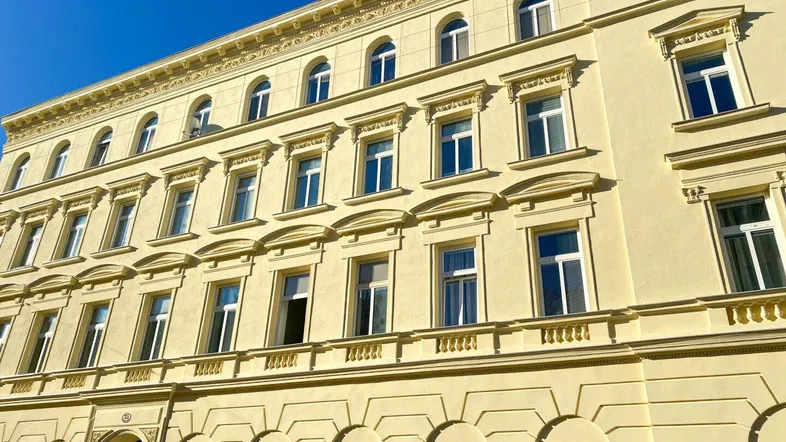 Detailansicht der historischen Fassade eines Altbaus mit vielen Fenstern und architektonischen Verzierungen.