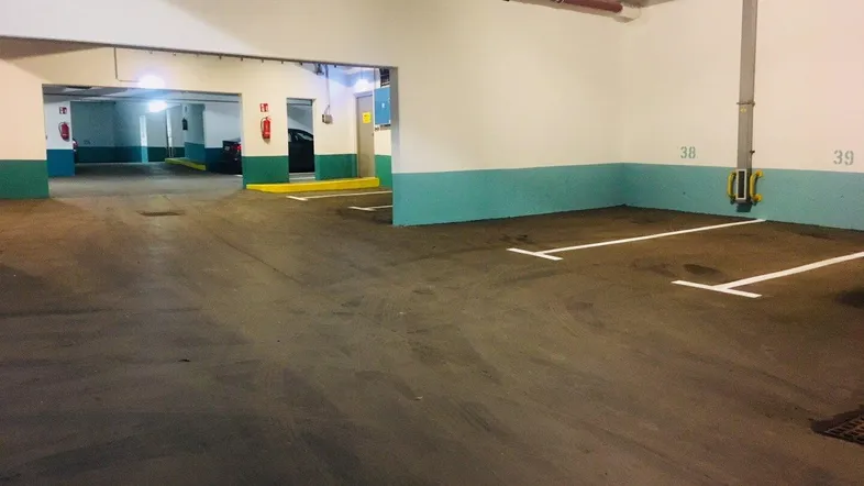 Geräumige Tiefgarage mit vielen markierten Stellplätzen und guter Beleuchtung für Fahrzeuge.